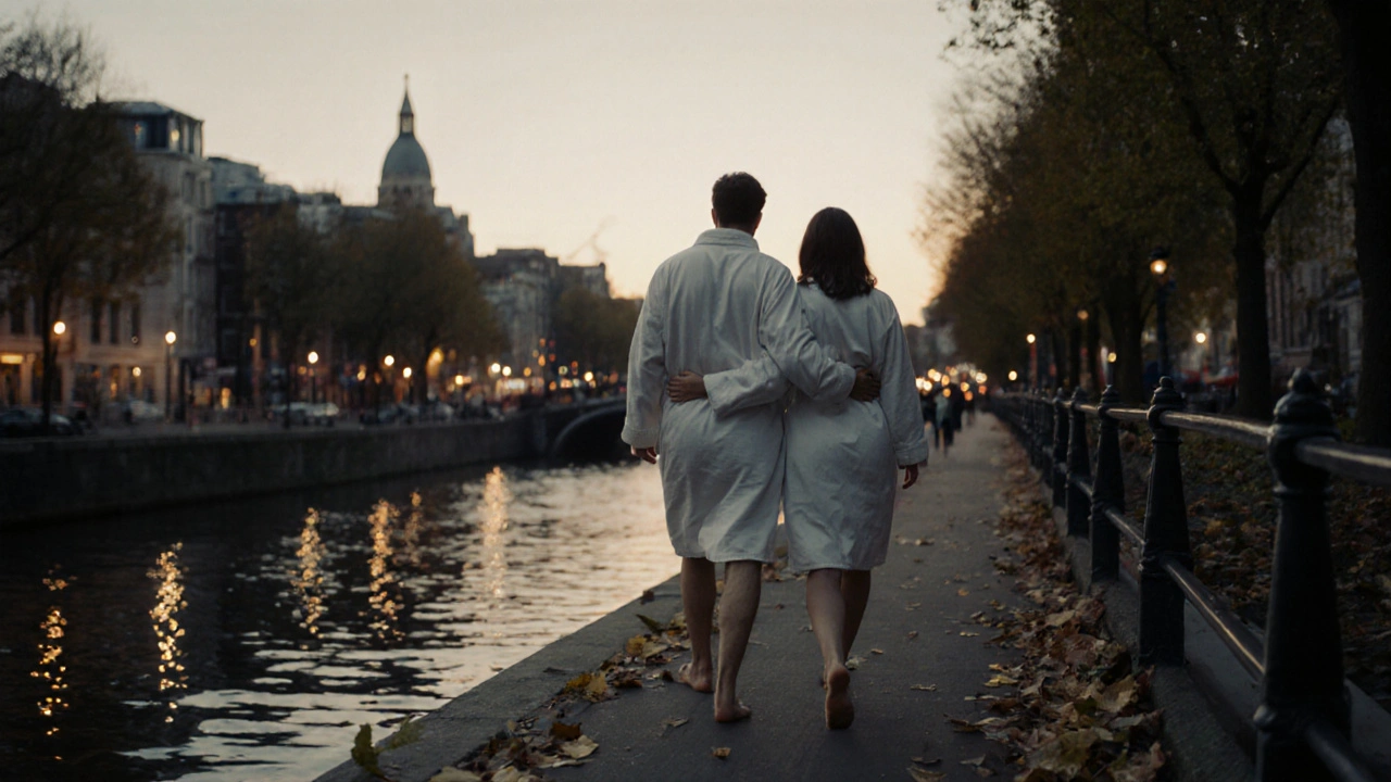 A couple walking barefoot along a canal at dusk in spa robes, shoulders touching, city lights reflecting on the water.